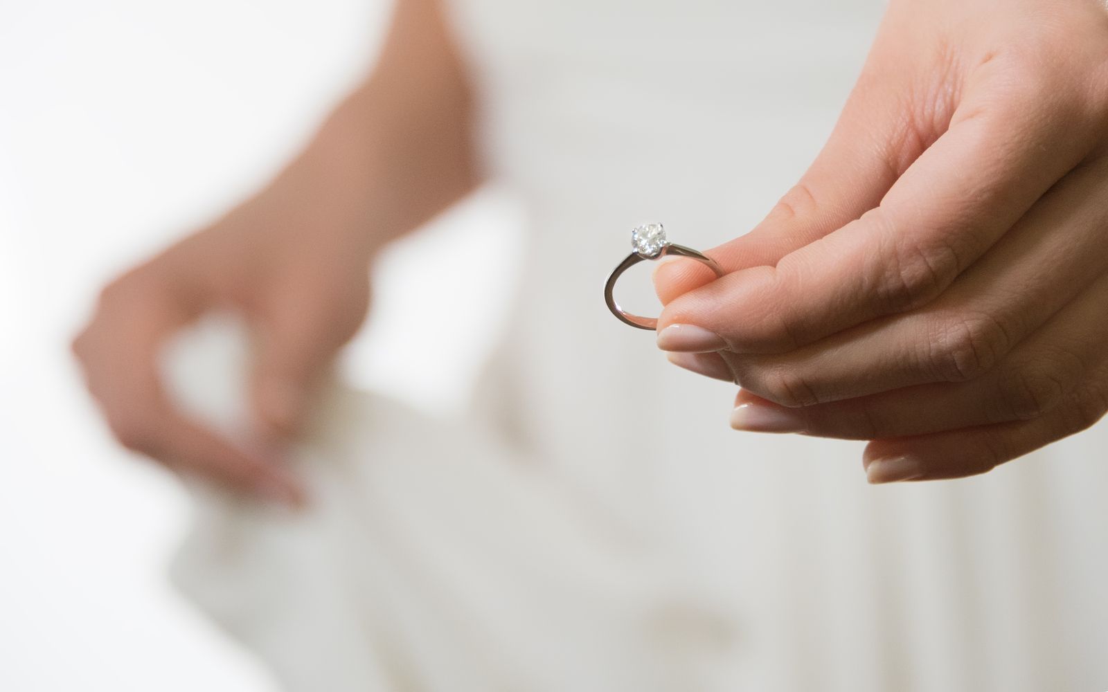 Eine Person hält einen goldfarbenen Ring mit einem Edelstein in die Kamera